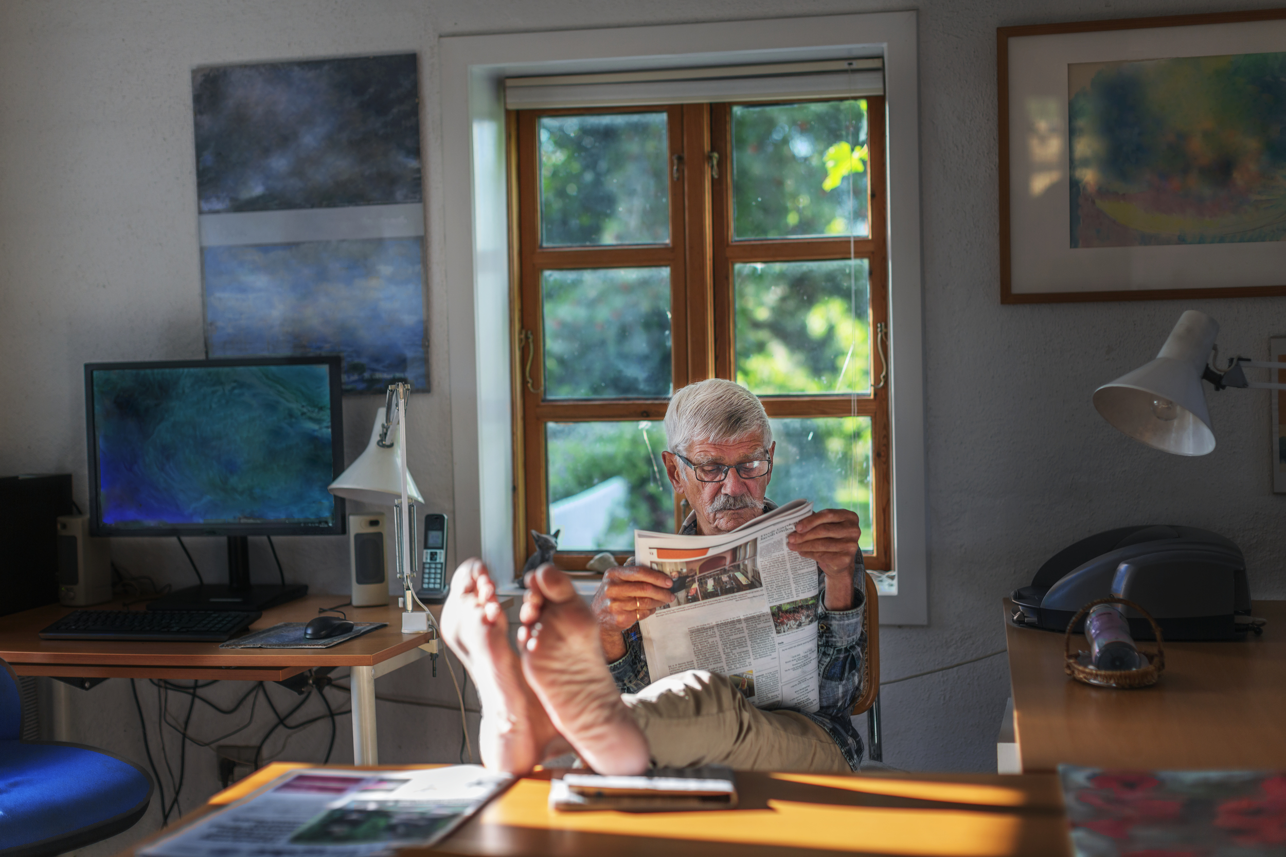 A elderly man is reading a newspaper.