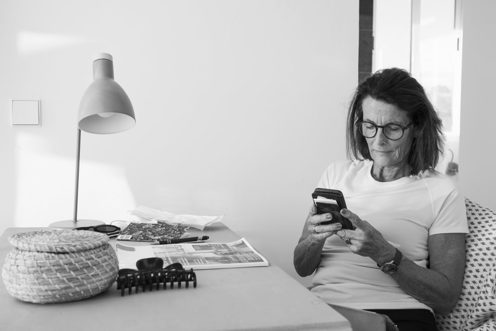 Woman reading on her phone in front of a newspaper on a desk.