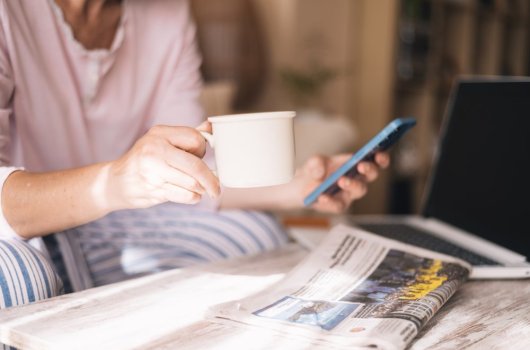 Person with phone, laptop and a newspaper 