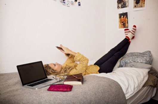Woman laying in bed holding a cell phone