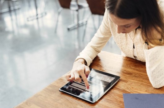 A woman sitting at a table with a tablet.