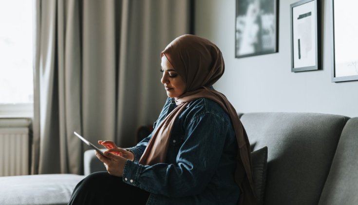 Woman sitting in a sofa holding an IPad 