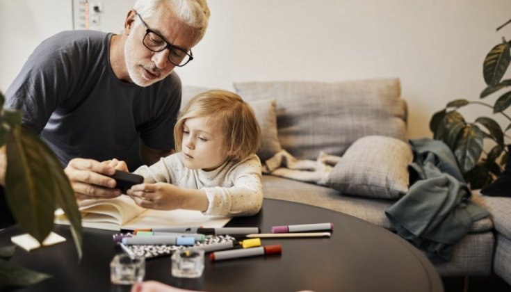 En man som visar sin mobiltelefon för ett barn