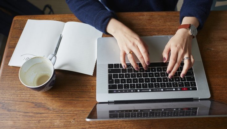 Två händer som skriver på en laptop.