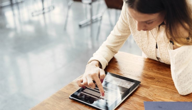 En kvinna sitter vid ett bord med en surfplatta.